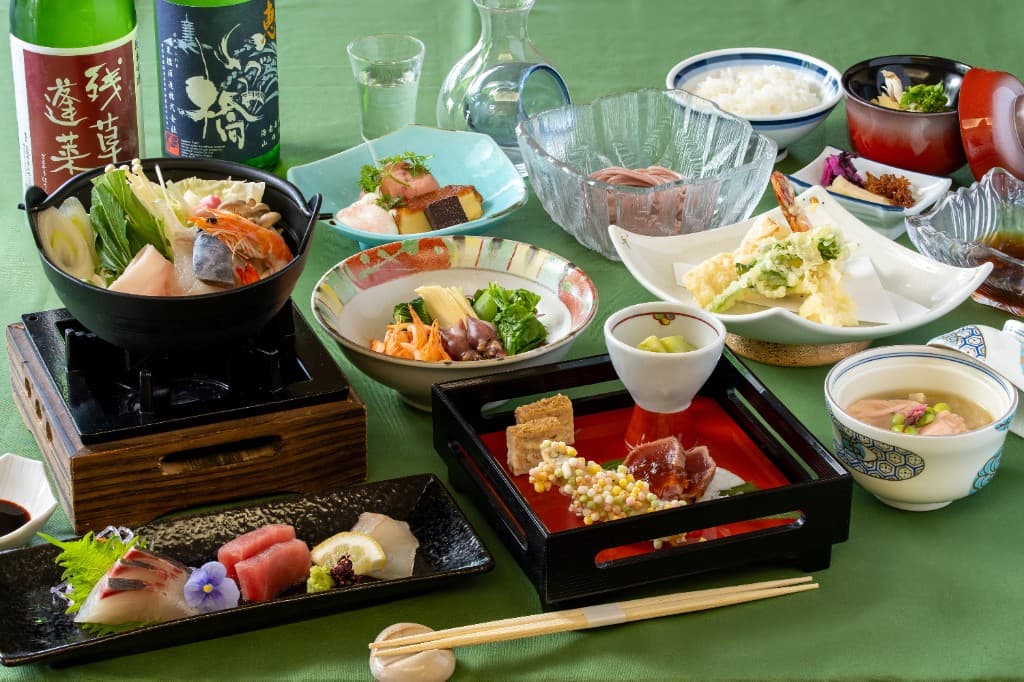 旬の食材を盛り込んだ会席料理の一例。刺身・天ぷら・鍋・小鉢・ご飯や汁物など多彩な一品が並ぶ